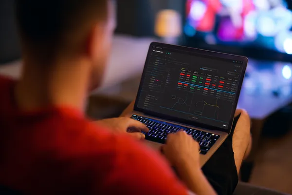 A man focused on his laptop with live stats in the background, highlighting the dedicated sports and gaming features of the 4777GEM mobile app.