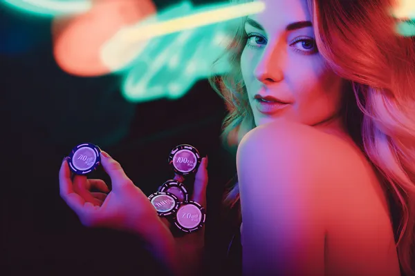 A glamorous woman holding casino chips in a neon-lit environment, representing the premium online casino atmosphere of 4777GEM.