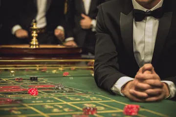 A professional dealer in a tuxedo greeting players at the roulette table, symbolizing the authentic live casino feel at 4777GEM.