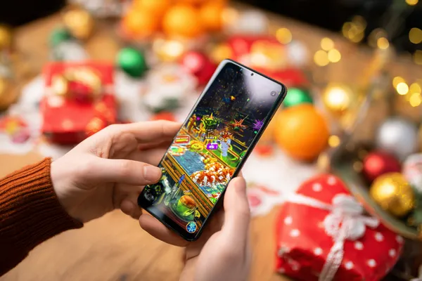 4777GEM Mobile Casino — Play anytime, anywhere A player using their smartphone during a festive local event, representing 4777GEM’s fully mobile-friendly casino.
